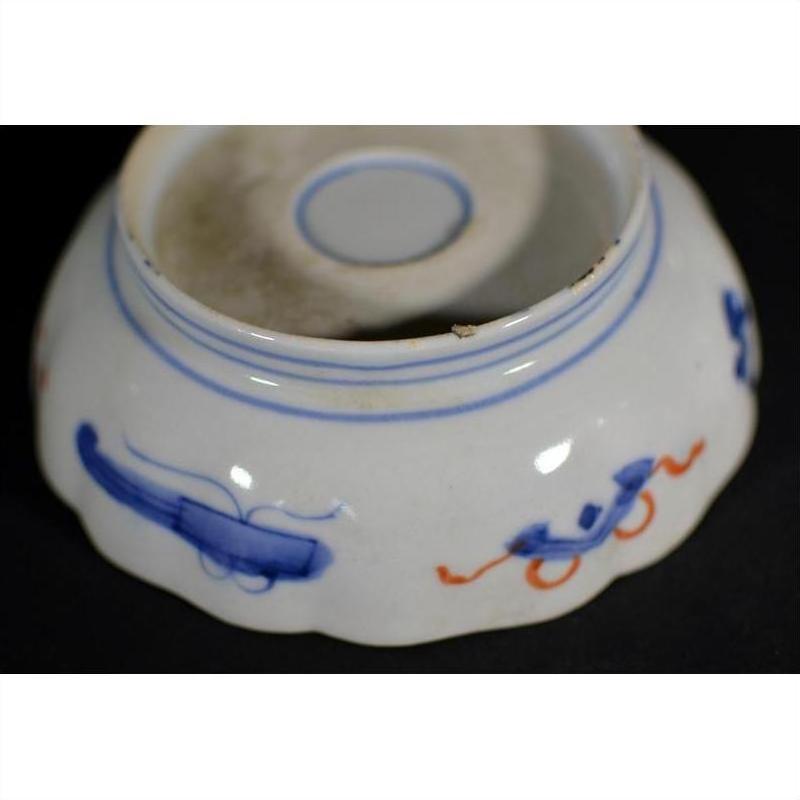 Close-up of the underside of a white and blue porcelain bowl with hand-painted patterns and scalloped edge.