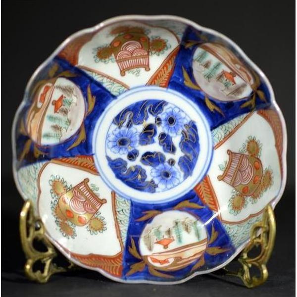 Blue, red, and gold hand painted Japanese Imari porcelain bowl with floral patterns displayed on a stand.