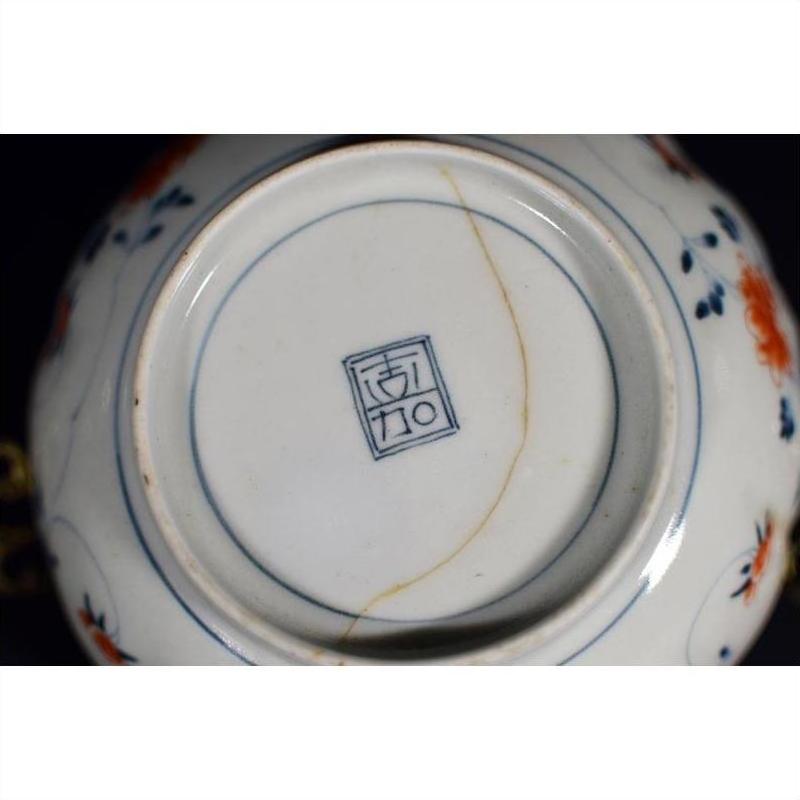 Close-up of base of antique hand-painted blue and white Japanese Imari porcelain bowl with maker’s mark and visible crack.