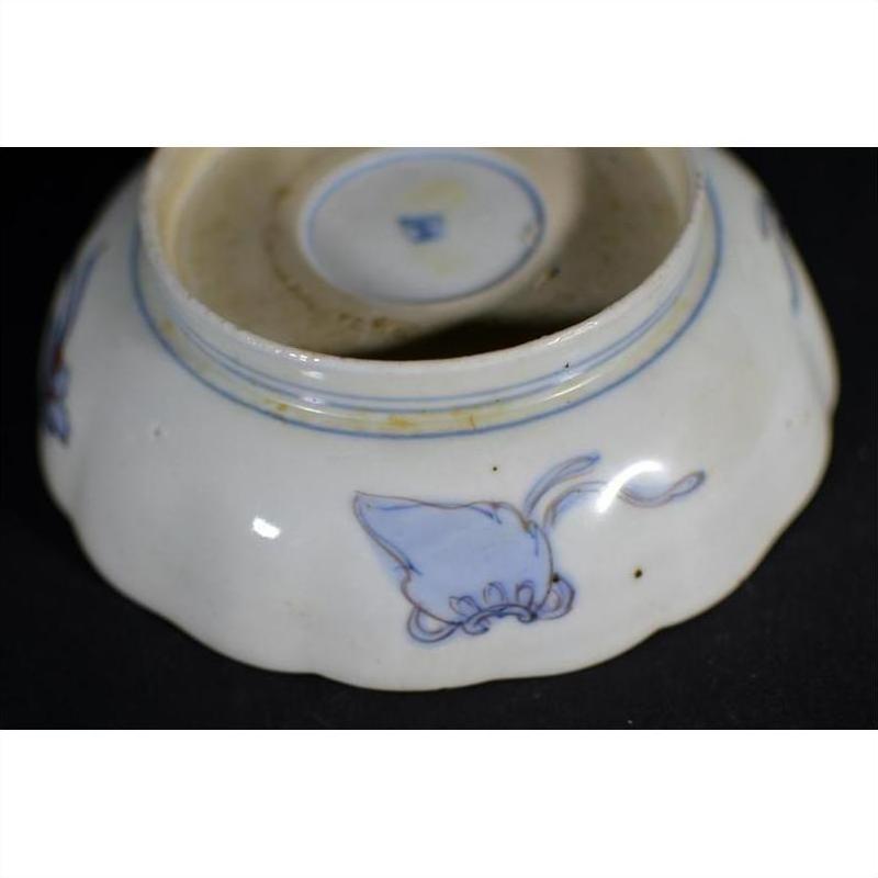 Close-up of blue and white porcelain bowl underside with hand painted butterfly motif, Imari style.
