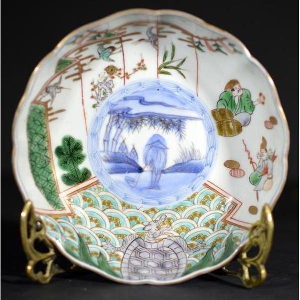 Multicolor porcelain Imari bowl with hand painted scenes and geometric patterns on brass stand, close-up.