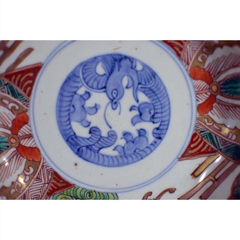 Close-up of an antique hand-painted porcelain Japanese Imari bowl with blue bird and cloud center motif.