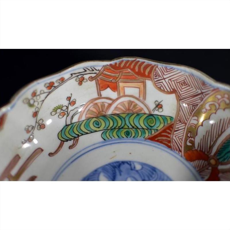 Close-up of a red, green, and blue hand painted porcelain Japanese Imari bowl with antique detailing.