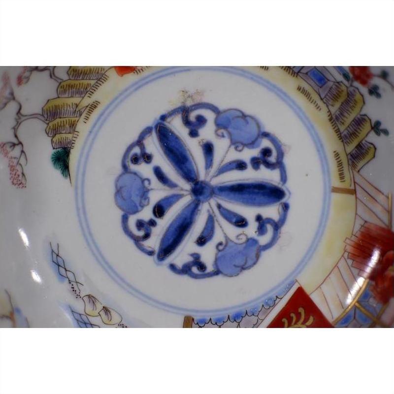 Close-up of four antique hand-painted Imari porcelain bowls with blue floral centers and multicolor decorative rims.