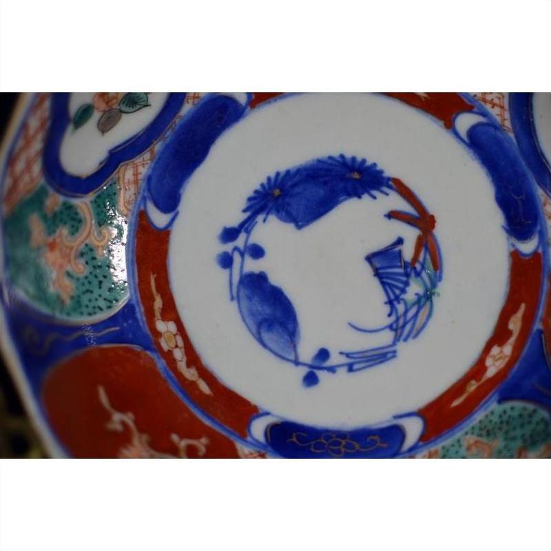 Close-up of four antique Imari porcelain bowls with blue, red, and green hand-painted floral and fish designs.