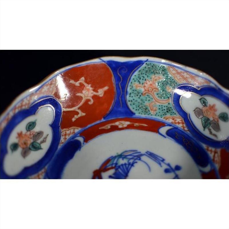 Close-up of four antique porcelain Imari bowls with red, blue, and green hand-painted floral rim patterns.