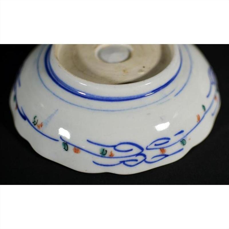 Porcelain bowls underside, set of four, hand-painted blue lines with orange and green accents, close-up.