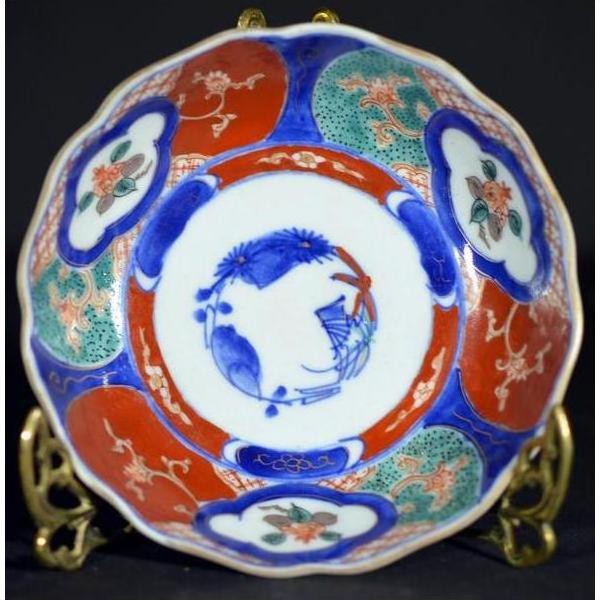 Close-up of four antique Imari porcelain bowls with vivid red, blue, and green floral and bird designs.