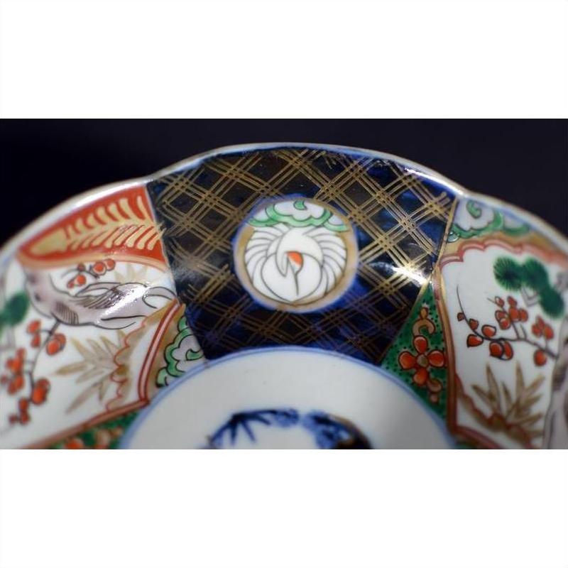 Close-up of antique hand painted Japanese Imari porcelain bowl with intricate red, green, black, and gold rim patterns.