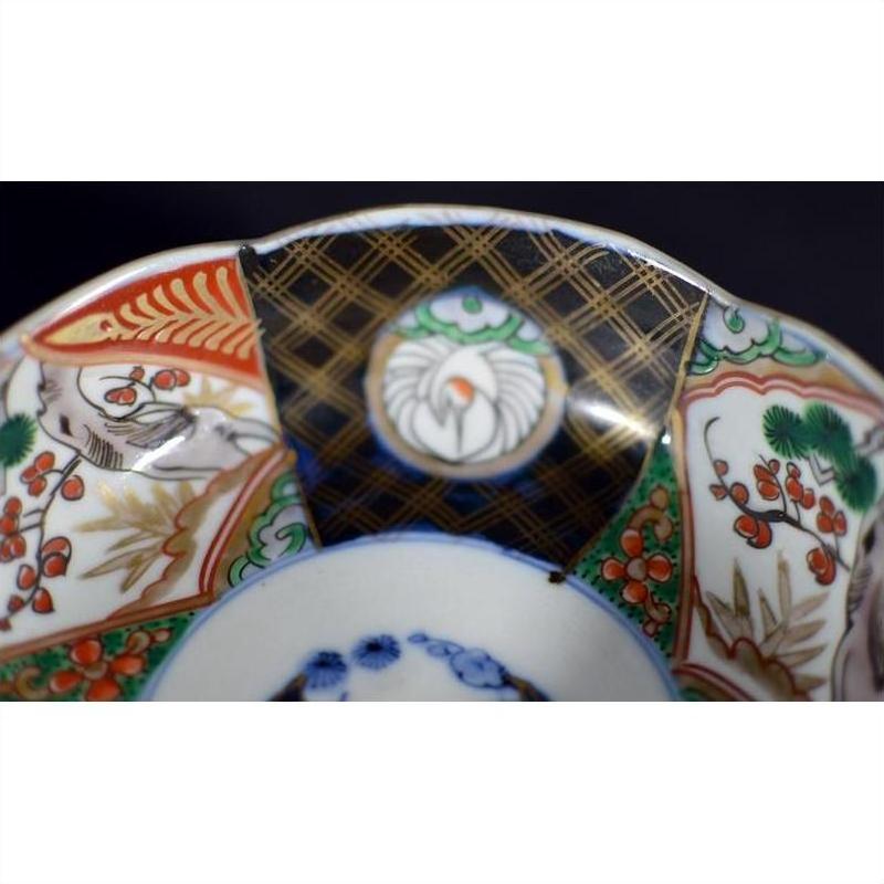 Close-up of colorful hand painted Imari porcelain bowl with floral patterns and black, gold-kintsugi accents.