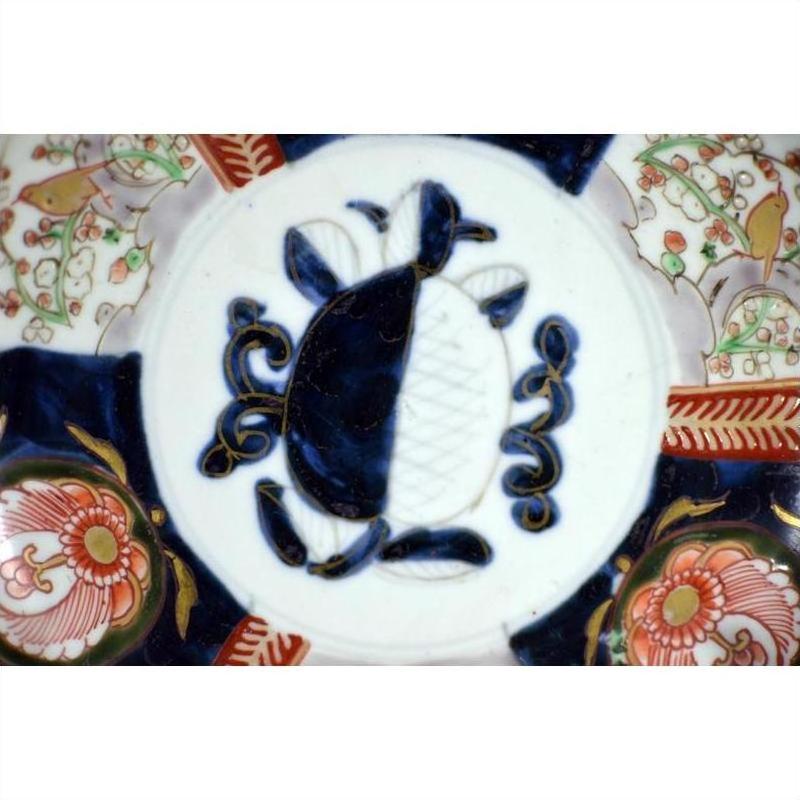 Blue and white porcelain Imari bowl with hand painted floral patterns and geometric center, close-up view.