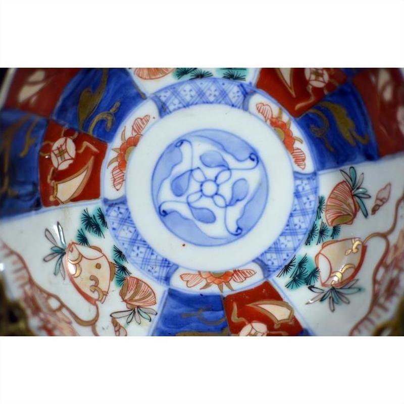 Close-up of a blue, red, and gold hand painted porcelain Japanese Imari bowl with floral and geometric patterns.
