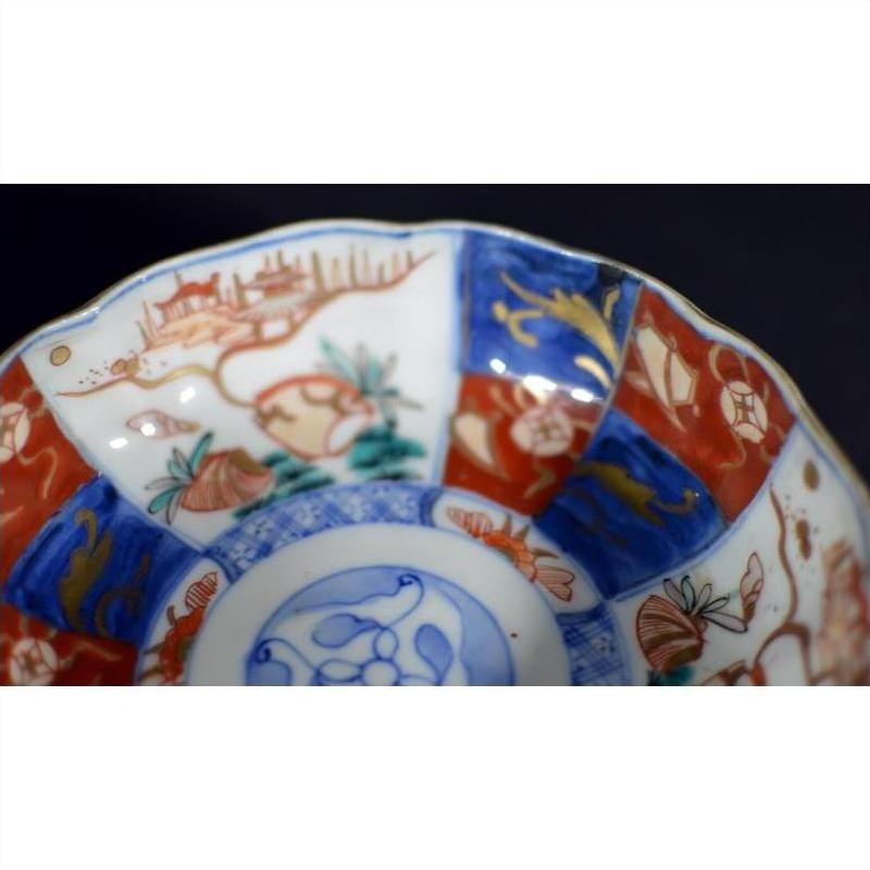 Close-up of antique Japanese Imari porcelain bowl with red, blue, and gold hand-painted floral patterns.