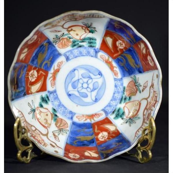 Colorful hand painted Japanese Imari porcelain bowl with floral and geometric patterns on a brass stand, close-up.
