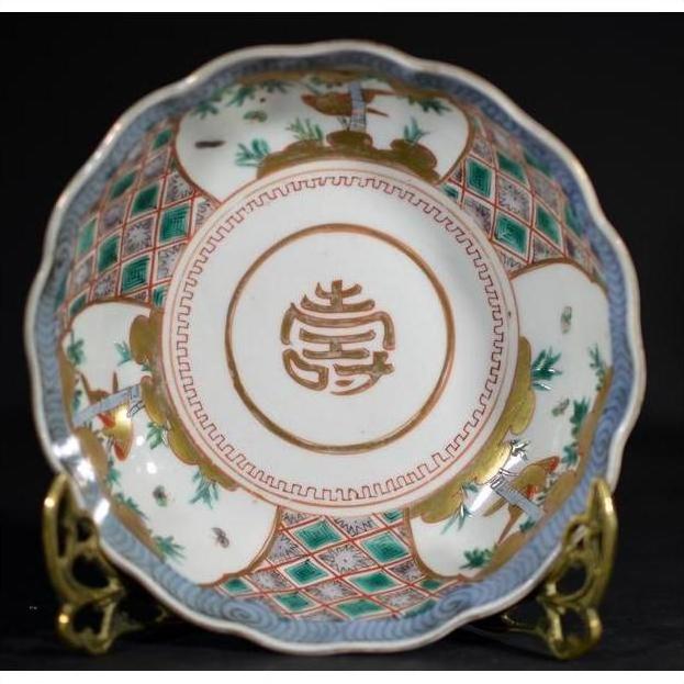 Blue and white porcelain Japanese Imari bowl with gold symbol and intricate patterns on a metal stand, close-up.
