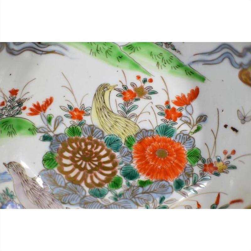 Close-up of a colorful porcelain Imari bowl with hand painted flowers, green leaves, and a yellow bird design.