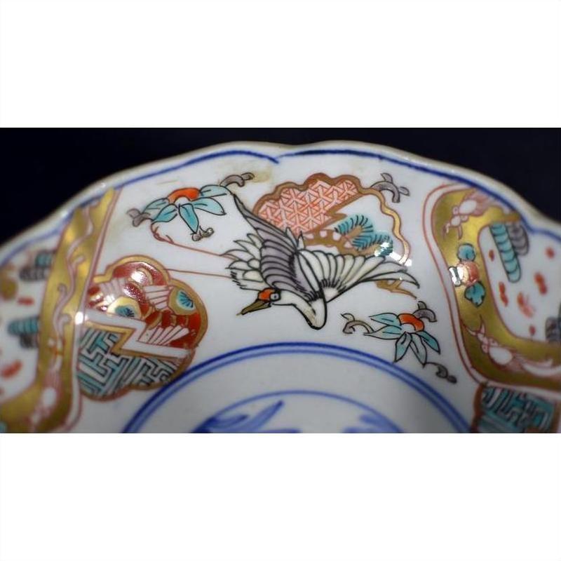 Close-up of a multicolored porcelain Japanese Imari bowl with hand painted bird and floral designs and a vibrant rim.