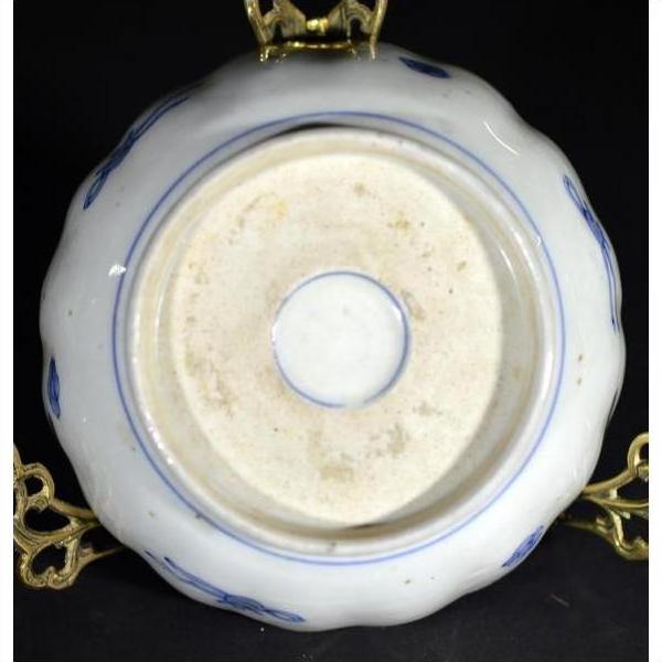 White and blue porcelain bowl underside on brass stand, hand painted Japanese Imari style, indoor setting.