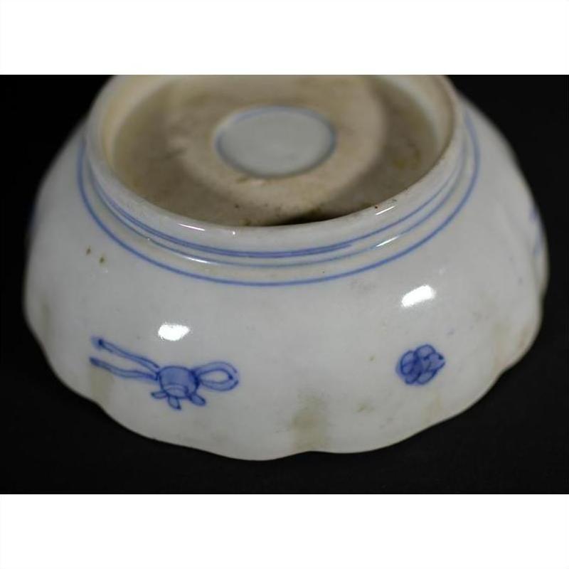 Close-up of blue and white porcelain bowl with hand-painted designs and rounded foot, placed indoors.