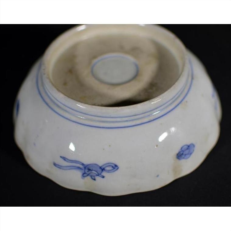 Blue and white porcelain bowl with hand-painted floral design, upside down on a dark surface.