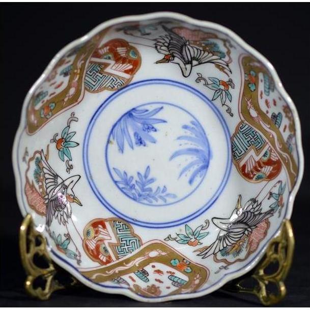 Red, blue, gold, and green hand painted Japanese Imari porcelain bowl with crane and floral designs, close-up view.
