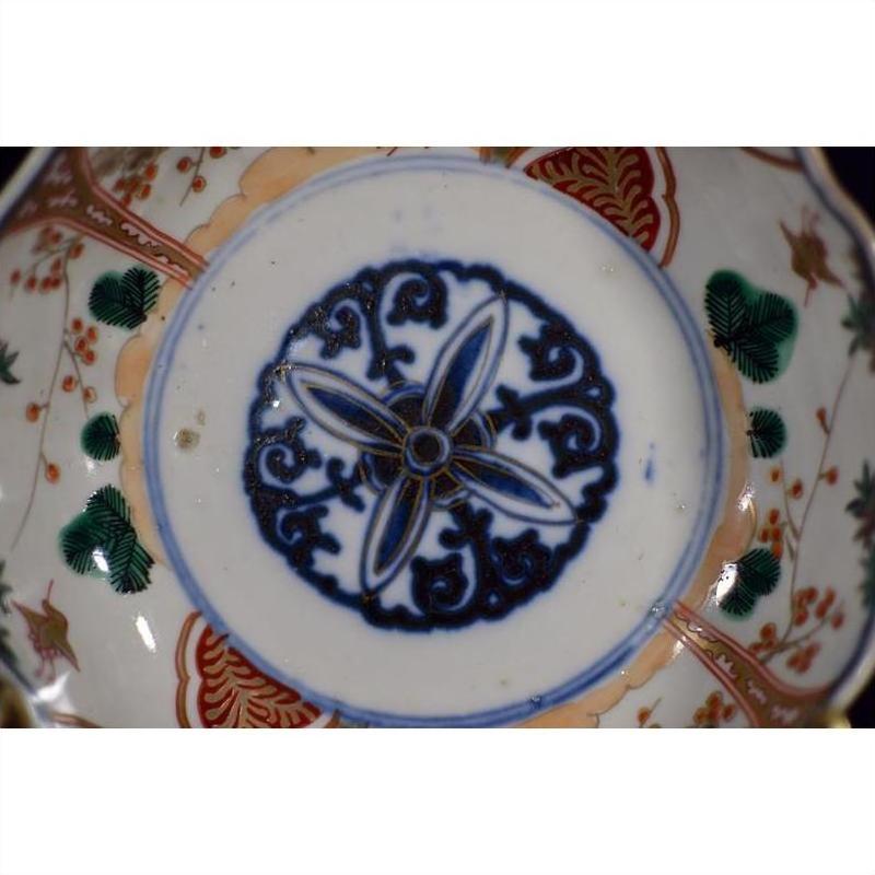 Close-up of blue and multicolored hand painted Japanese Imari porcelain bowl with floral center on white background.