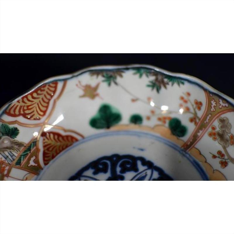 Red, green, and gold floral and geometric patterns on hand painted Japanese Imari porcelain bowl, close-up view.