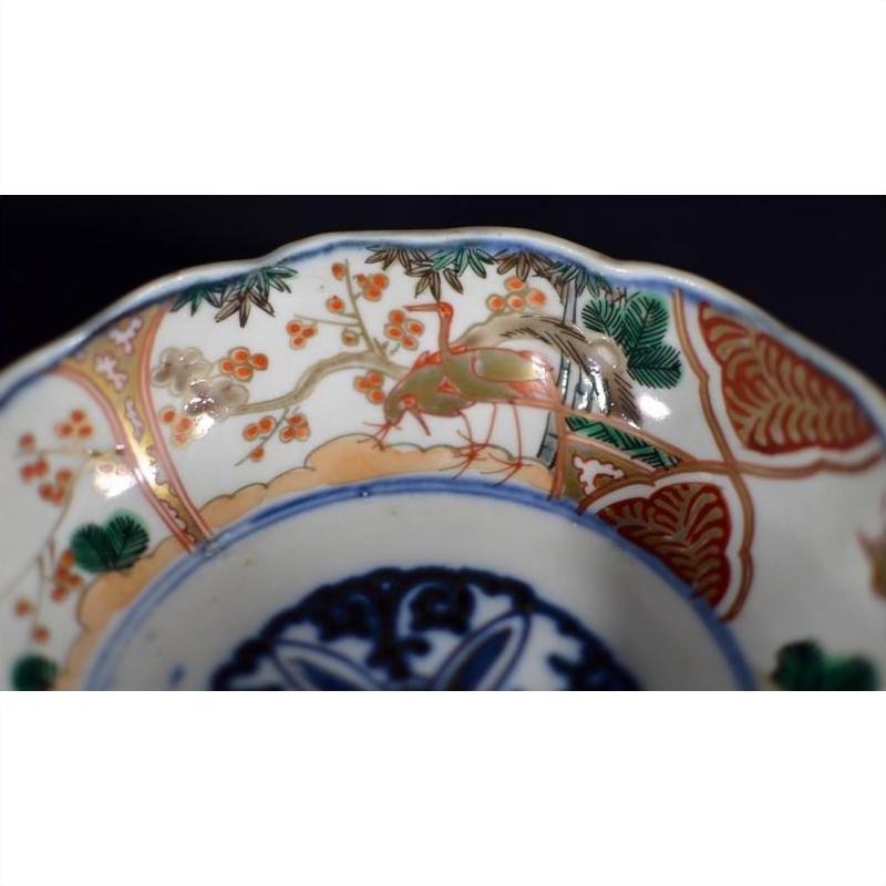 White porcelain Imari bowl with intricate green, gold, red, and blue floral and bird designs.