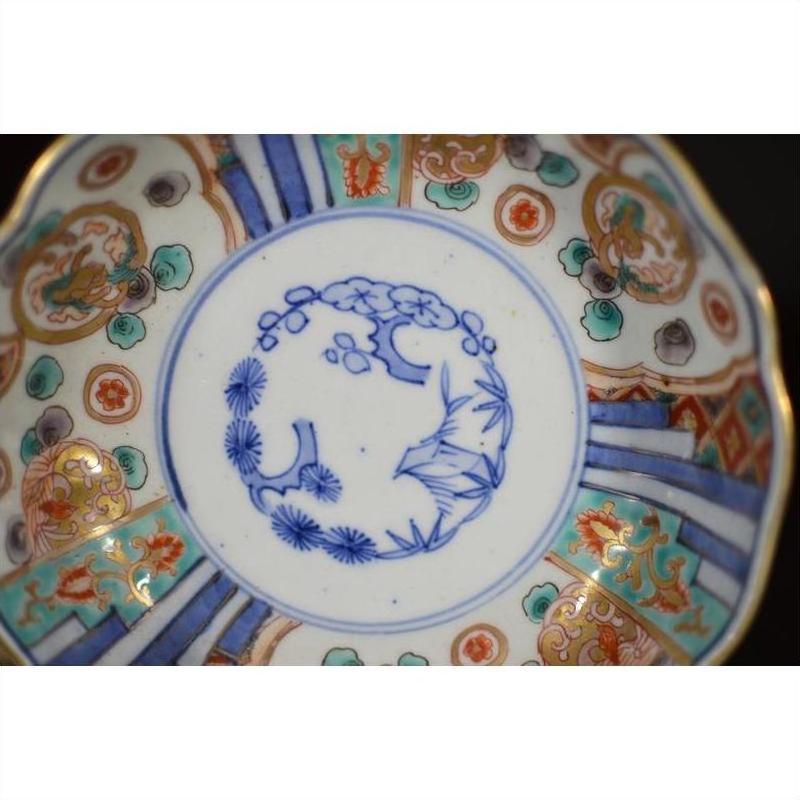 Blue, red, and gold hand painted Imari porcelain bowl with central floral design, close-up view.