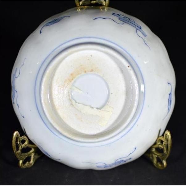 Close-up of blue and white porcelain Imari bowl bottom, hand painted, displayed on a brass stand.