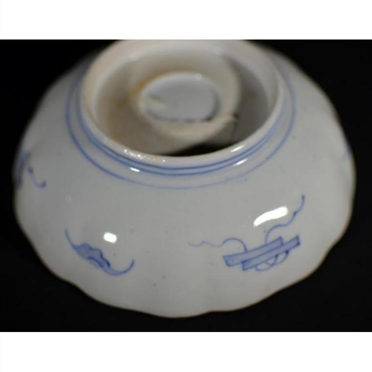 Blue and white porcelain bowl with hand-painted motifs, upside down on black surface.