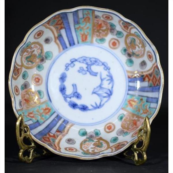 Blue and red hand painted Japanese Imari porcelain bowl on ornate metal stand, close-up.