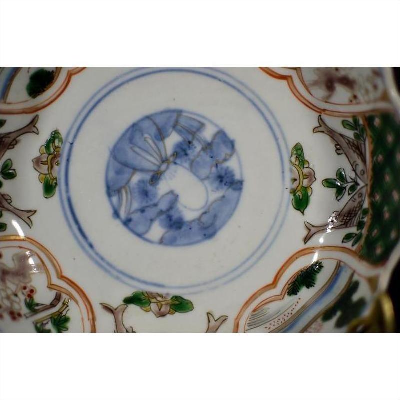 Close-up of blue, green, red, and gold hand painted patterns on antique Japanese Imari porcelain bowl.