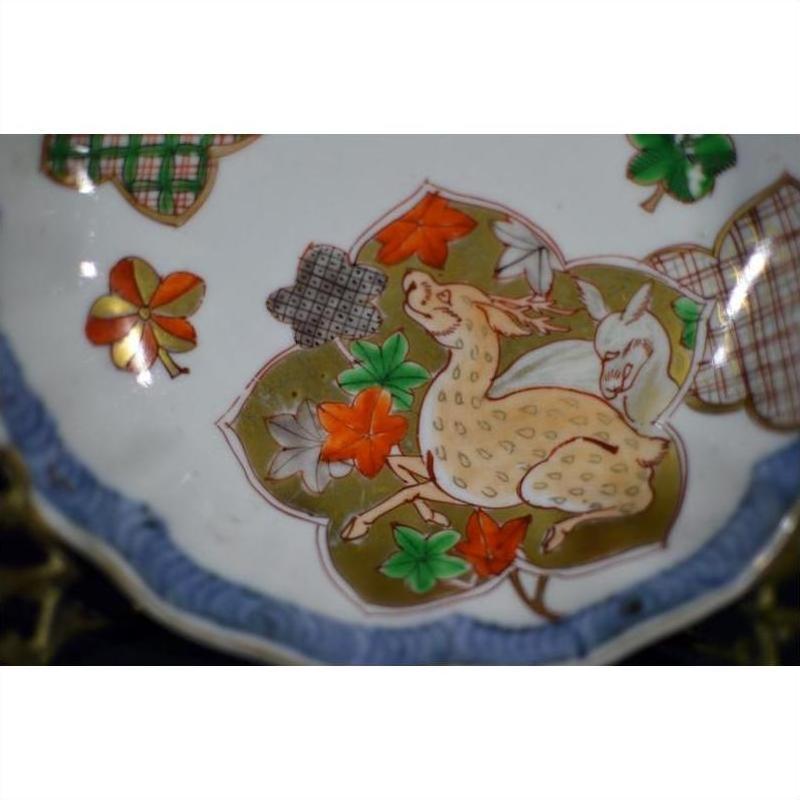 Close-up of an antique hand painted Japanese Imari porcelain bowl with a deer among colorful leaves and patterns.
