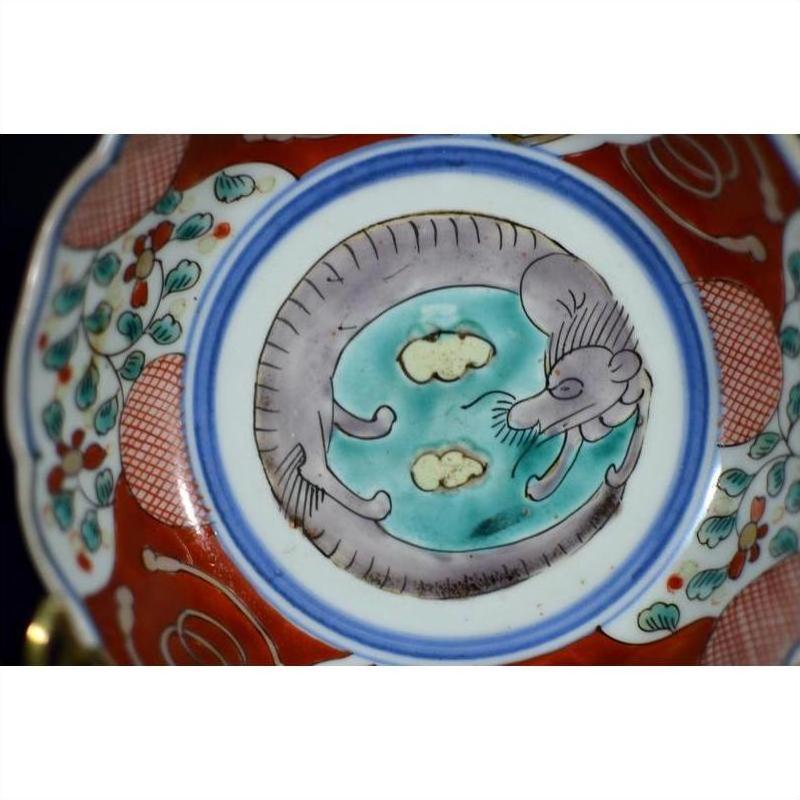Close-up of red, blue, and white Imari porcelain bowl with hand-painted rat or mouse among clouds design.