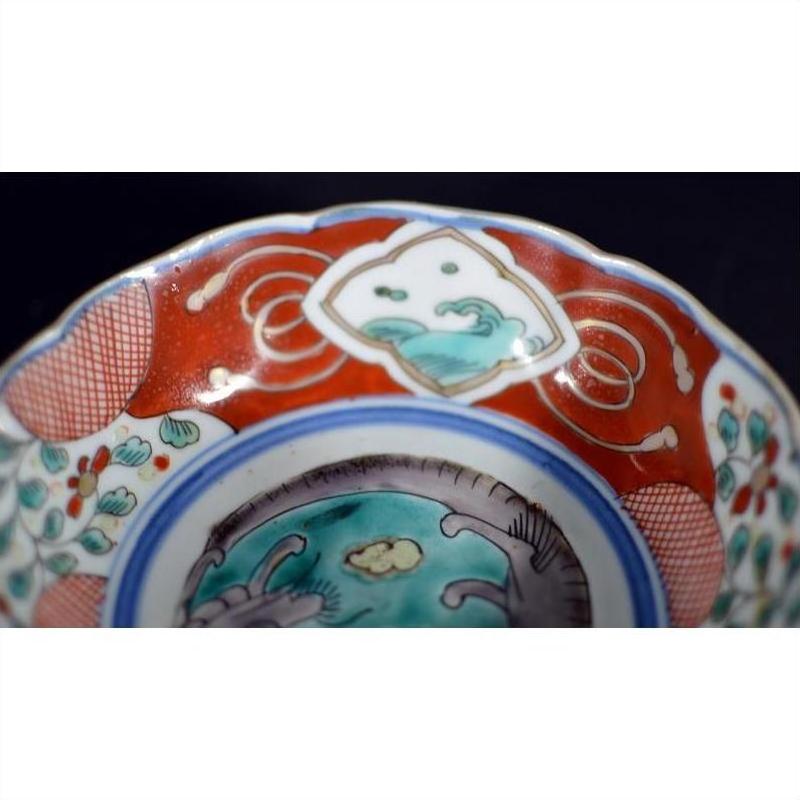Close-up of a red, blue, and green floral Japanese Imari porcelain bowl with hand-painted designs.