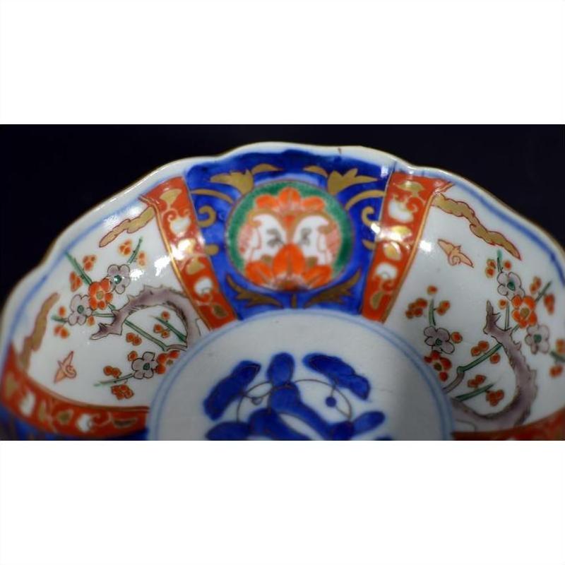 Red, blue, green, and gold hand painted Imari porcelain bowl with floral patterns, close-up view.