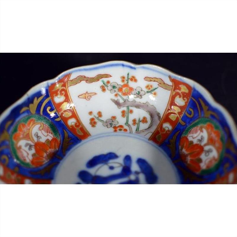 Close-up of blue, red, and gold floral Japanese Imari porcelain bowl with unique central scene.