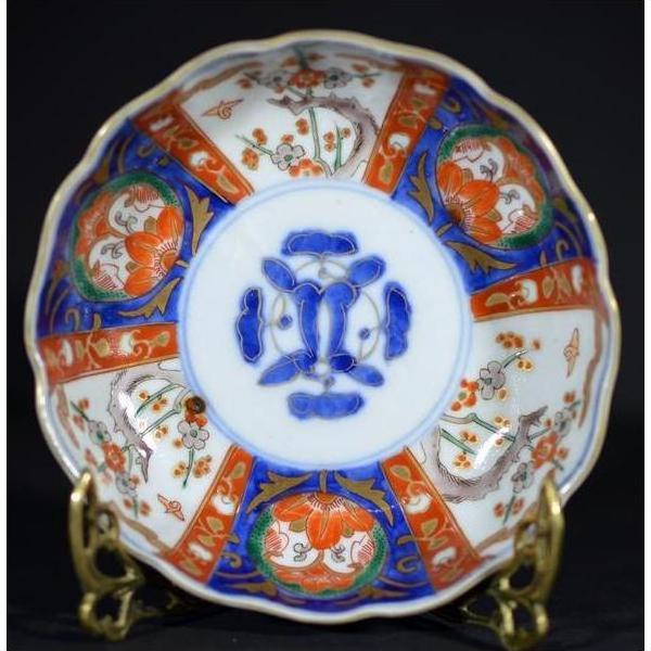Close-up of a hand painted Japanese Imari porcelain bowl with vibrant floral patterns on a gold stand.