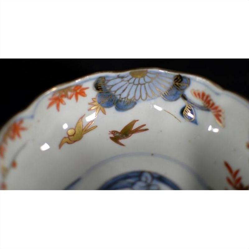 Close-up of blue, gold, and red hand painted porcelain Imari bowl with floral patterns and two birds.