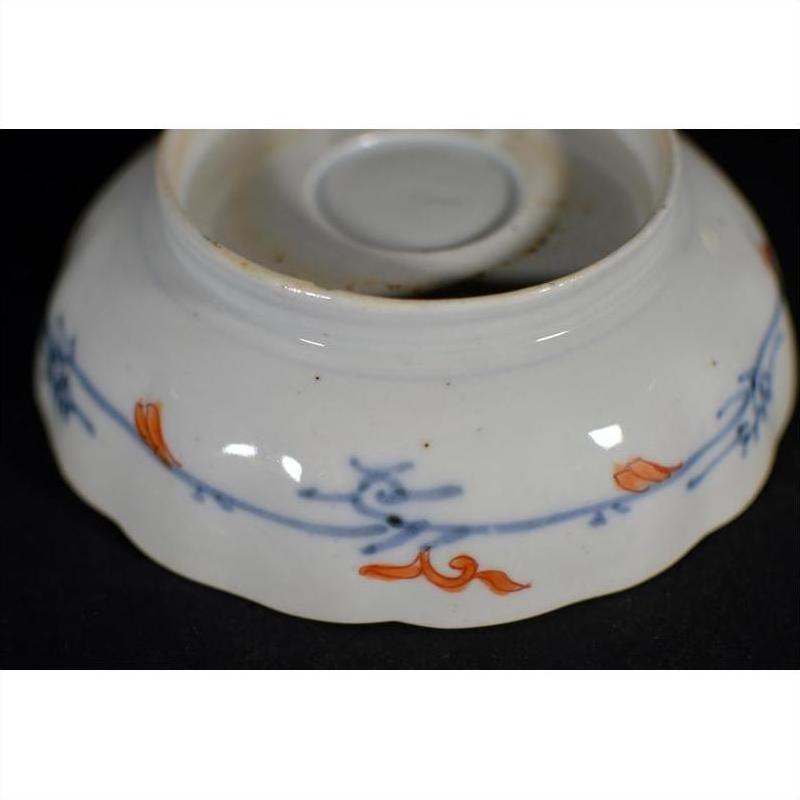 White porcelain bowl bottom with blue and orange floral designs, close-up, hand painted Japanese Imari style.