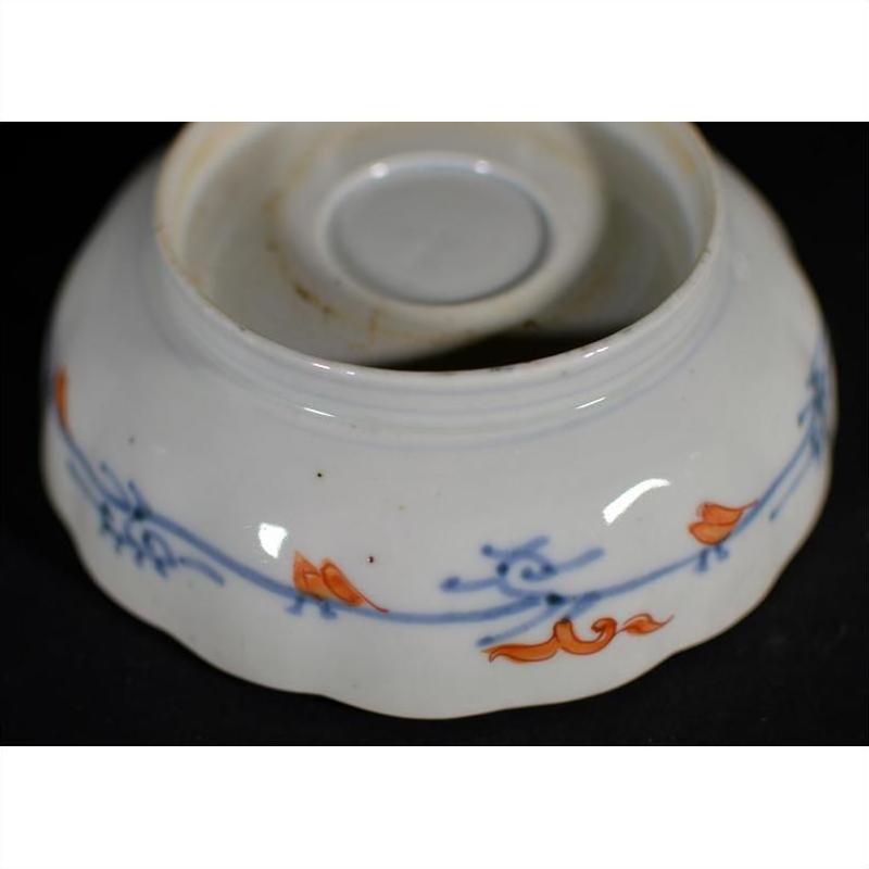 Blue and orange porcelain bowl with floral designs, upside down on a black surface.
