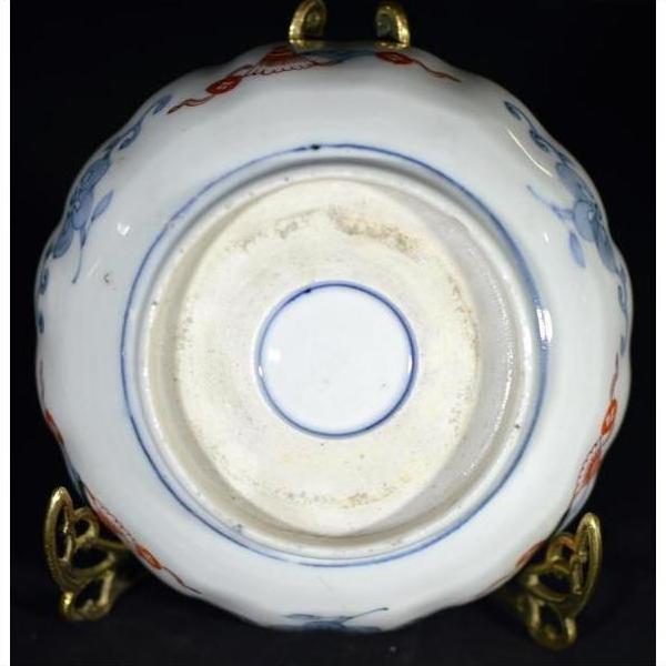 Close-up of the underside of an antique hand painted Japanese Imari porcelain bowl on a brass stand.