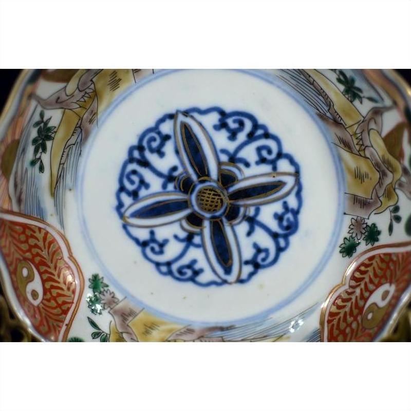 Close-up of antique hand painted Japanese Imari porcelain bowl with blue floral and red fish design inside.