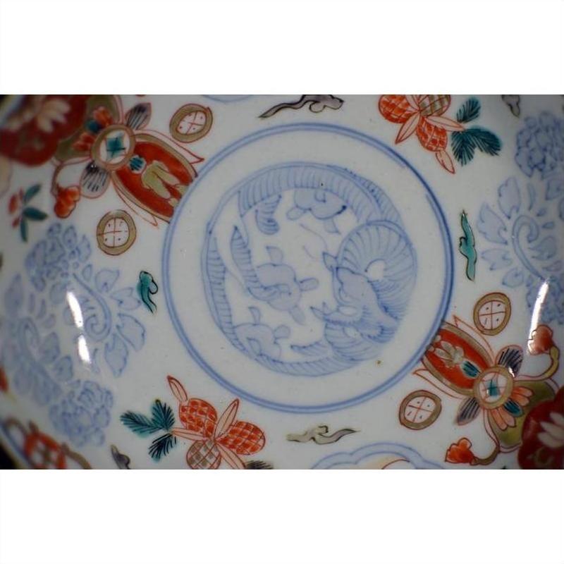 Close-up of blue, red, and gold hand painted Japanese Imari porcelain bowl with floral and animal motifs.