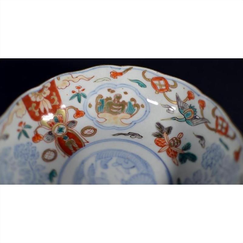Close-up of antique Japanese Imari porcelain bowl with hand painted red, blue, and gold floral patterns.