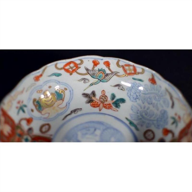 Close-up of a Japanese Imari porcelain bowl, hand painted with red, blue, green, and gold floral and animal designs.