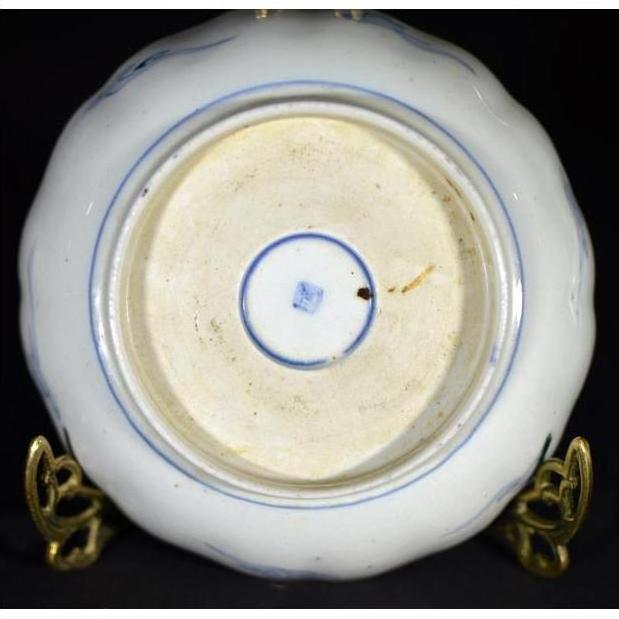 White and blue porcelain bowl underside on brass stand, hand painted in Japanese Imari style, indoor setting.