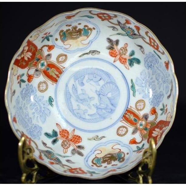 Close-up of a red, blue, and gold hand painted Japanese Imari porcelain bowl on a brass stand.