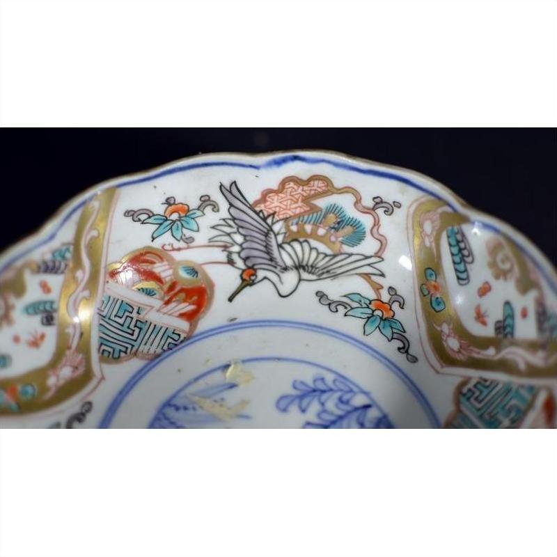 Close-up of a red, blue, green, and gold porcelain Japanese Imari bowl with crane and floral patterns.